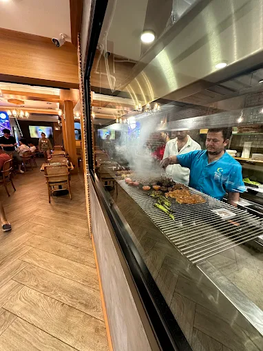 Open kitchen with chef preparing food at the grill